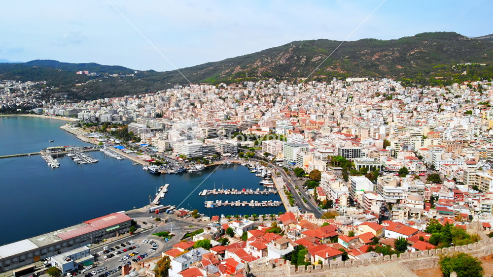 Aerial view of Kavala, a lot of buildings, Aegean sea coast, sea port, ancient fort, green hills in the distance, Greece