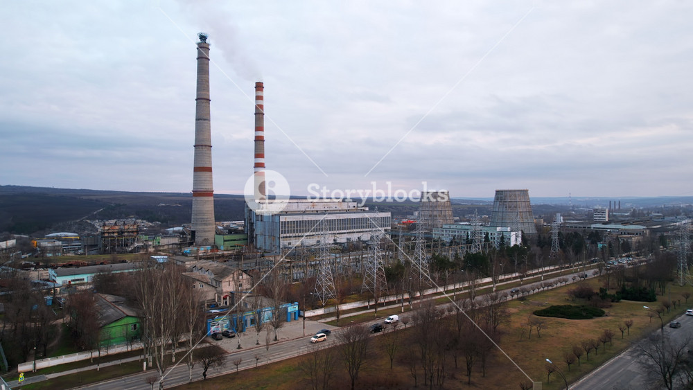 Aerial drone view of thermal power plant in Chisinau at cloudy weather, Moldova. View of pipes with felling steam, buildings and bare trees around
