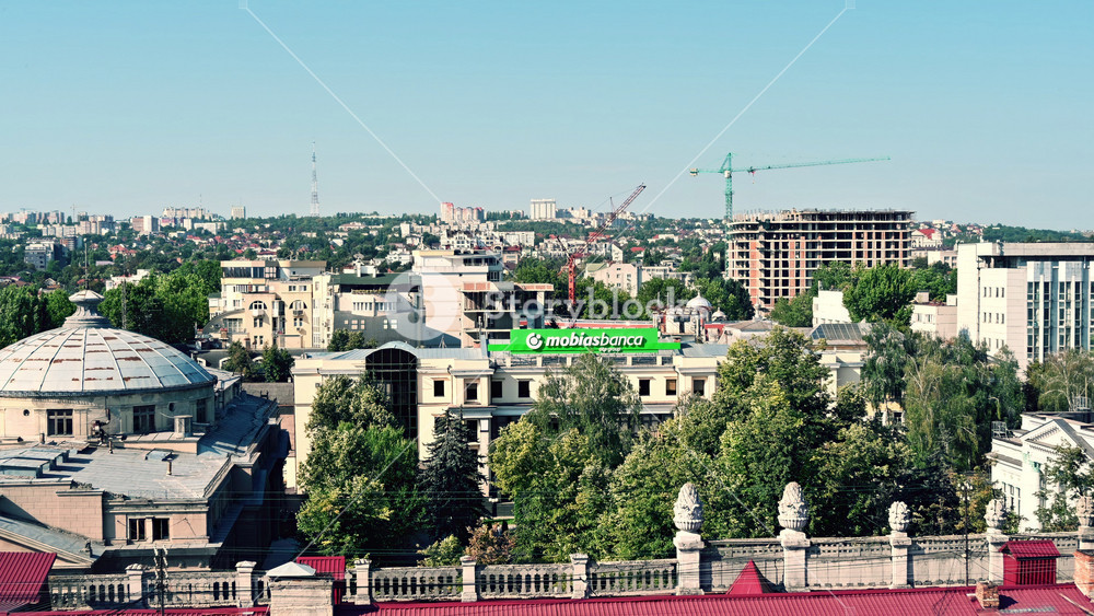 Chisinau, Moldova - September 10,2025: Aerial view of an urban city with modern buildings, green trees, and cranes in the background under a clear blue sky