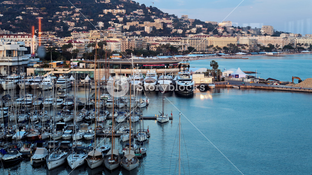 Cannes, France - March 15, 2025: View of multiple boats docked in the Cannes Marina with the buildings of the city on the background at sunset