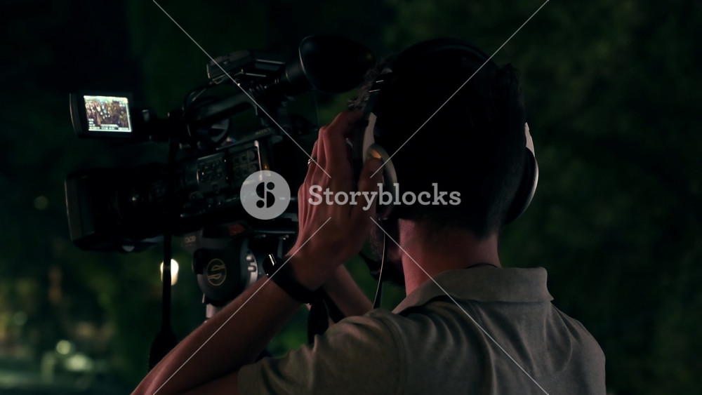 CHISINAU, MOLDOVA - JUNE 30, 2021: Professional cameraman recording poeple watching football in a public place at night