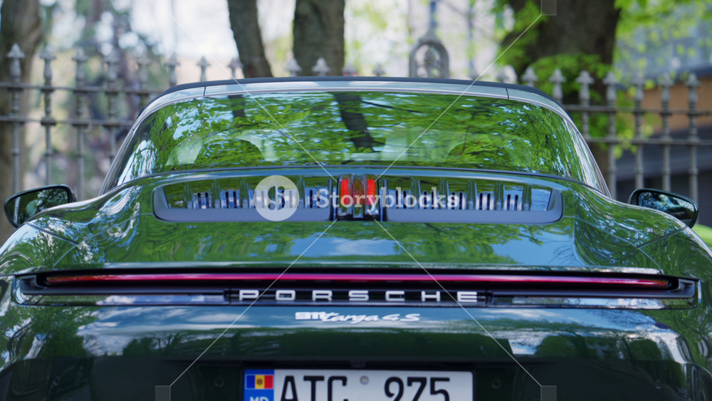 Chisinau, Moldova - April 17, 2026: Rear view of a luxury green Porsche sports car parked outdoors, showing detailed design, exhaust, and branding