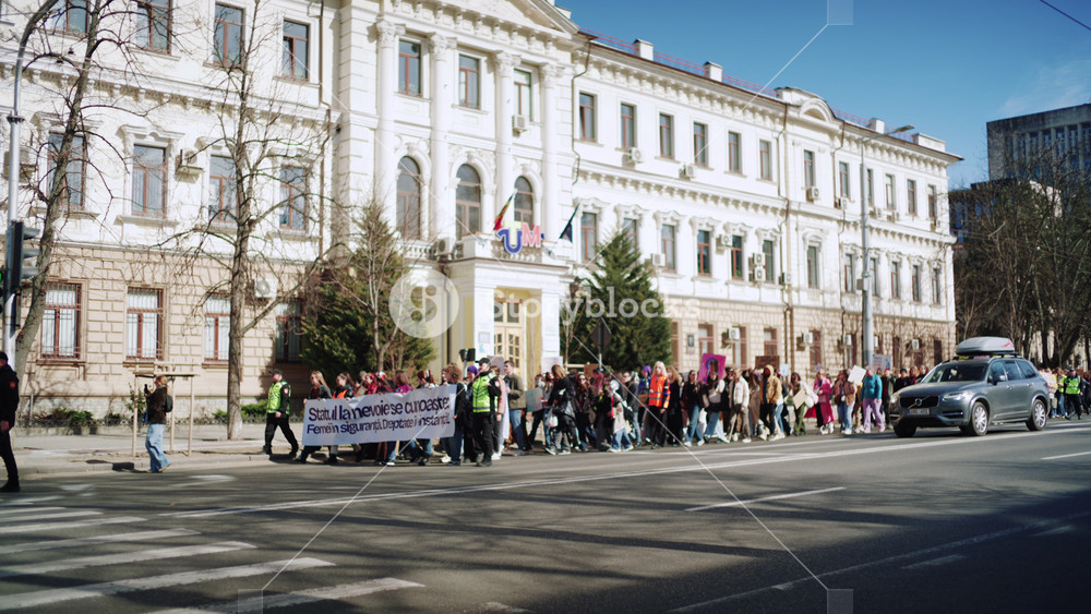 Chisinau, Moldova - March 8, 2026: Group of people marching in a protest with banners dedicated to International Women's Day on the street in the city center