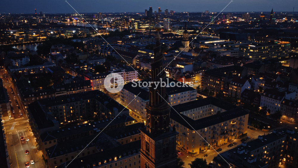 Aerial drone view of the skyline with the famous spiral spire of the Church of Our Saviour lit against the evening sky in Copenhagen, Denmark