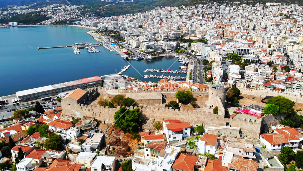 Aerial view of Kavala, a lot of buildings, Aegean sea coast, sea port, ancient fort, green hills in the distance, Greece