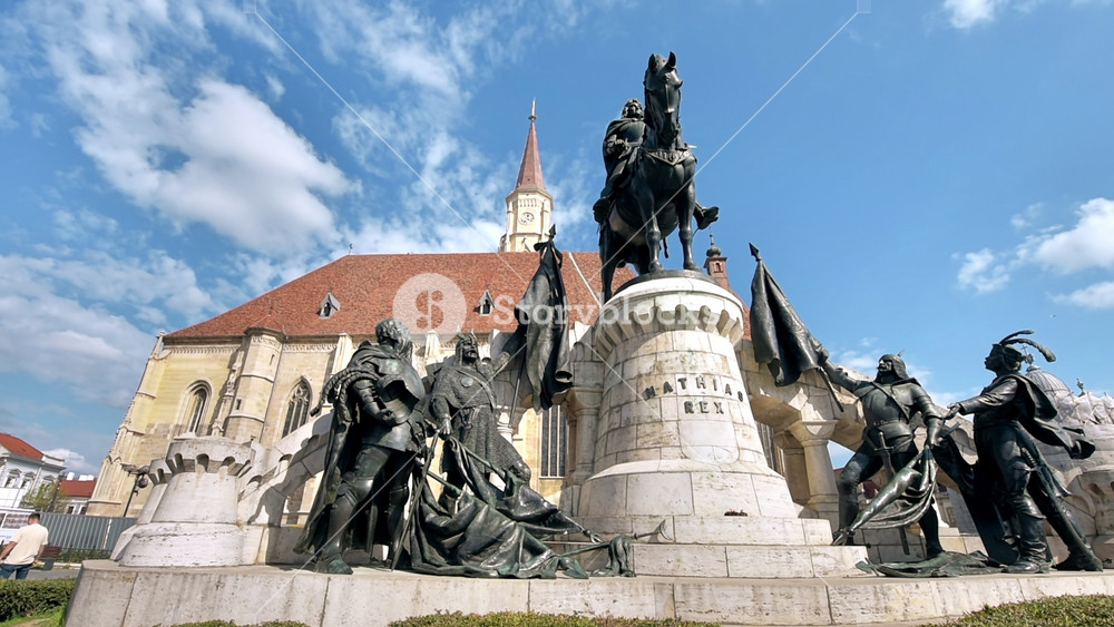 CLUJ, ROMANIA - APRIL, 2022: Street scape of Cluj centre, Romania. Central square with Saint Michael Church and statue of Matthias Corvinus in front of it, walking people