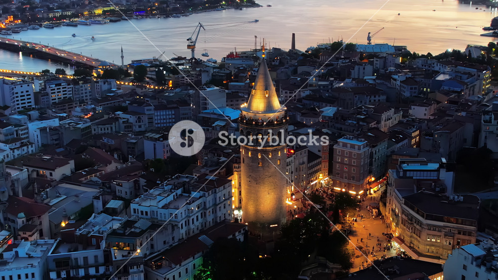 Aerial drone view of Istanbul at sunset, Turkey. Multiple residential buildings around the Galata tower, nightlights, Golden Horn waterway on the background
