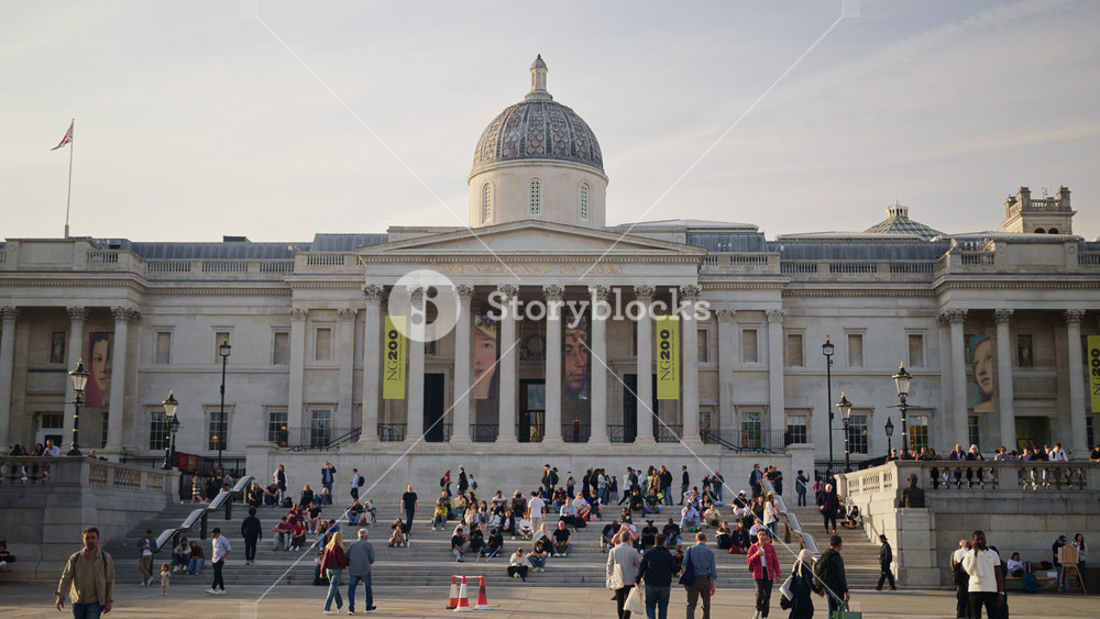 London, England - May 14, 2025: People sitting and moving on the steps of the The National Gallery museum in daylight. Trafalgar Square