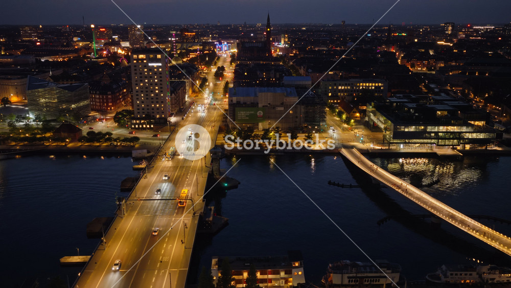 Copenhagen, Denmark - August 6, 2025: Aerial drone view of Amager and Christianshavn at night, with glowing streets, Our Saviour's Church tower, and the harbor in the distance