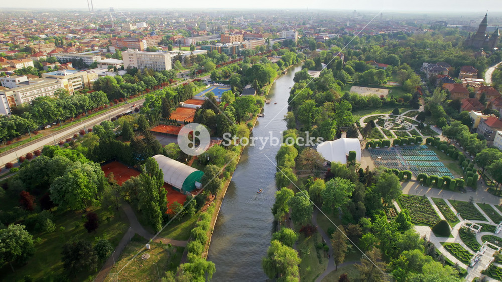Aerial drone view of Bega river in Timisoara, Romania. View of the river with floating boats, greenery on the both sides of the river and bridge with moving cars, cityscape