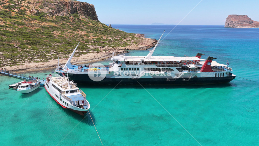 Balos, Greece - June 15, 2026: Aerial drone view of boats moored at the Balos jetty in clear turquoise water by the rocky shore