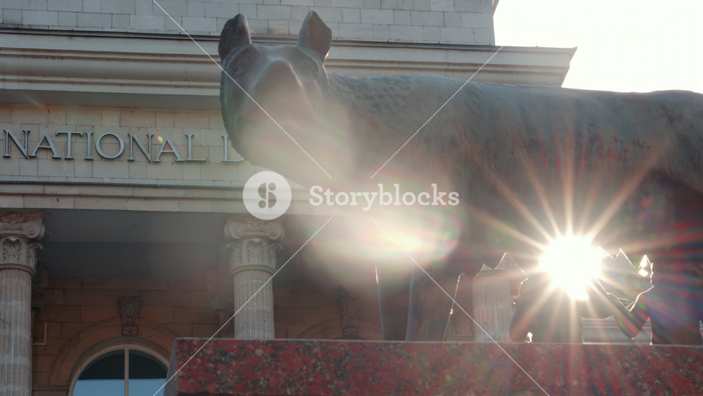 Chisinau, Moldova - September 25, 2025: Historic bronze statue of the Capitoline Wolf with Romulus and Remus on a red marble pedestal in front of the National History Museum of Moldova
