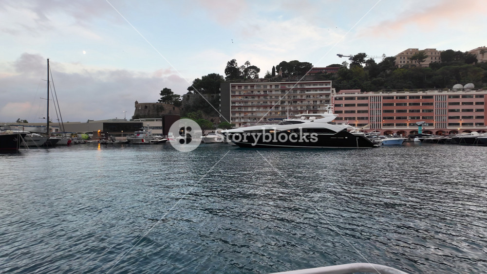 La Condamine, Monaco - July 4, 2025: Row of sleek luxury yachts, docked in Port Hercules with the Monaco cityscape and misty hills in the background