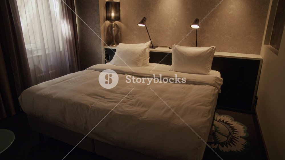 No people establishing shot of empty double bed with linens illuminated by bedside lamps in hotel room, perfect for travel agency promotions, hotel booking websites or real estate listings