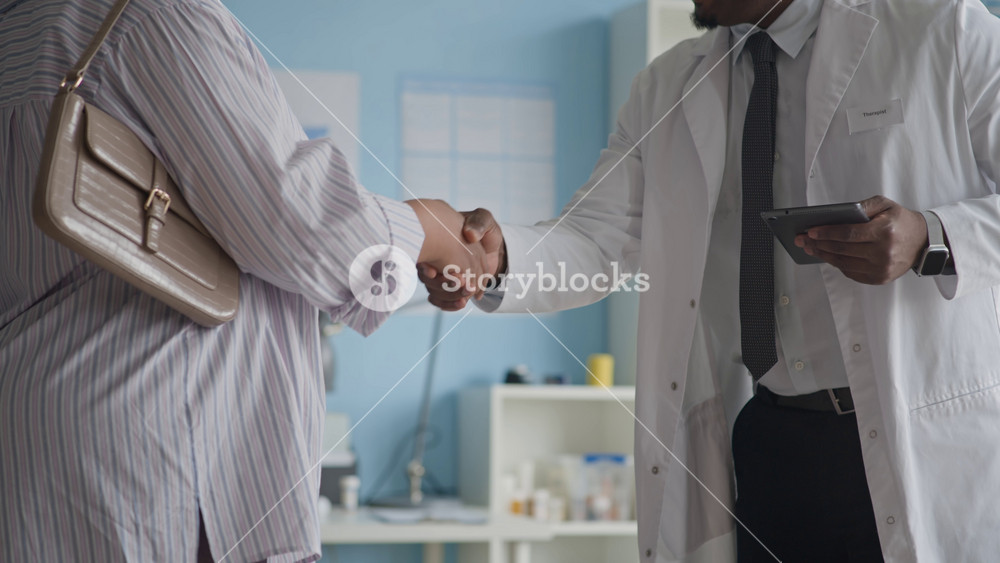 Tilt up of Biracial expectant mother and her doctor shaking hands during prenatal appointment, symbolizing trust, respect, and professional care in supportive medical setting
