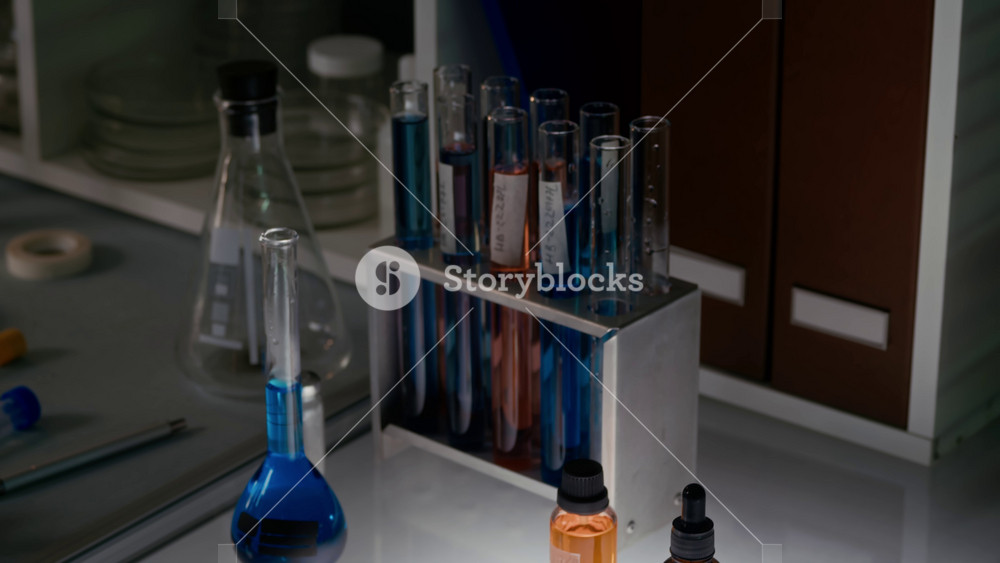 No people tilt up shot of work desk in scientific laboratory with sterile petri dishes, glass flask and rack of test tubes filled with liquids