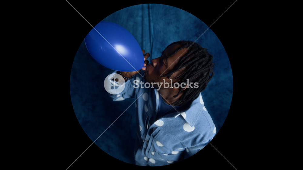 African American young adult man blowing up blue balloon and letting it fly away. Clip is ideal for party planning advertisements, mental health concepts, or creative lifestyle marketing campaigns