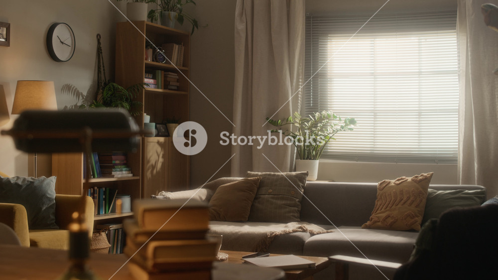 Establishing no people shot of warm and stylish living room interior with sofa, armchair, wooden furniture and decorative plants in natural daylight