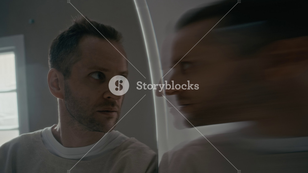 Young adult Caucasian man in psychiatric clinic looking at distorted, blurry mirror reflection and smiling insanely. Clip is perfect for mental health campaigns or cinematic thriller projects