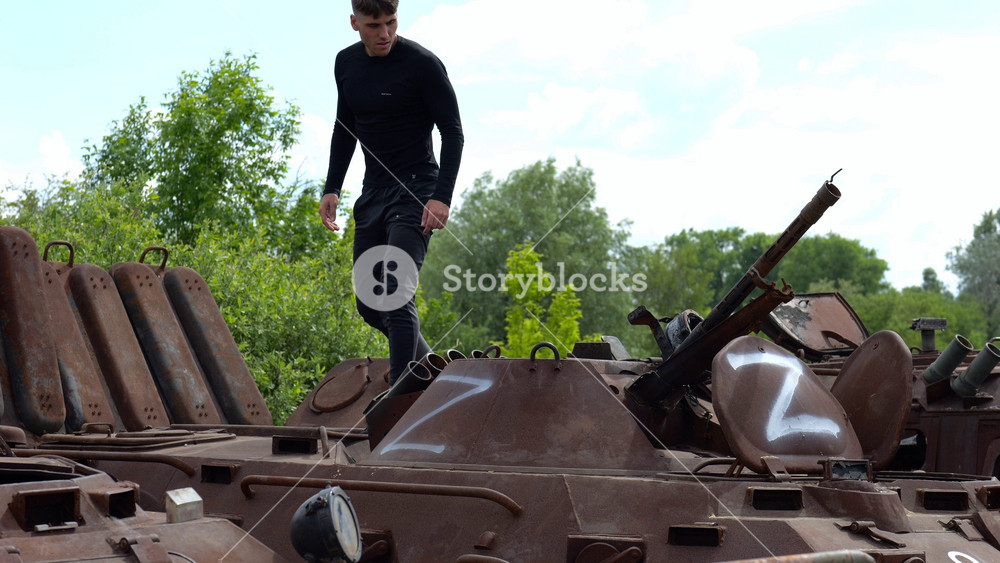 Young man looking at destroyed military equipment of the russian army. Exhibition of rusty and burned-out armored vehicles on ukrainian territory. War between Ukraine and russia. Slow motion