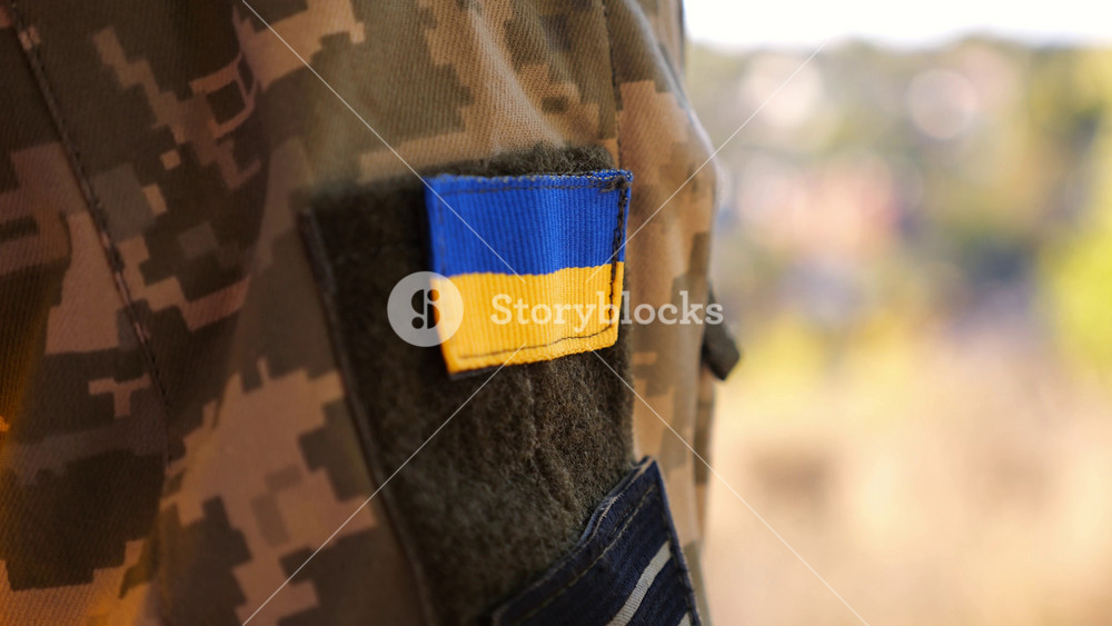 Close up of military blue-yellow chevron on shoulder of soldier at countryside. This emblem embodies the unbreakable spirit and pride of the