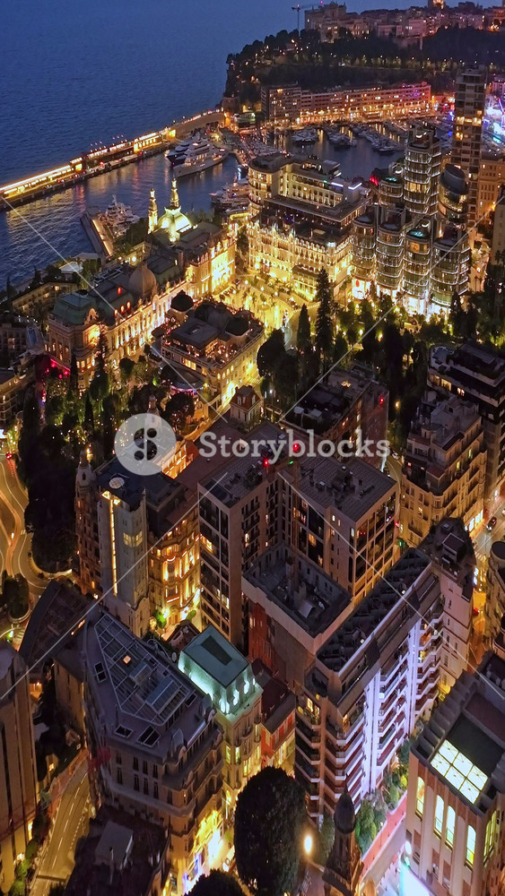 Aerial establishing shot of illuminated city buildings. Aerial view of illuminated skyscraper in residential city at night, Monte Carlo