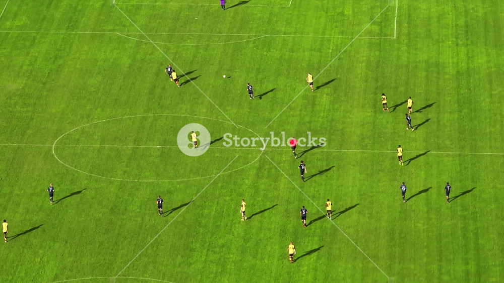 The camera flies over the green football field where professionals run and compete with each other. A football match filmed from a drone with a parallax effect