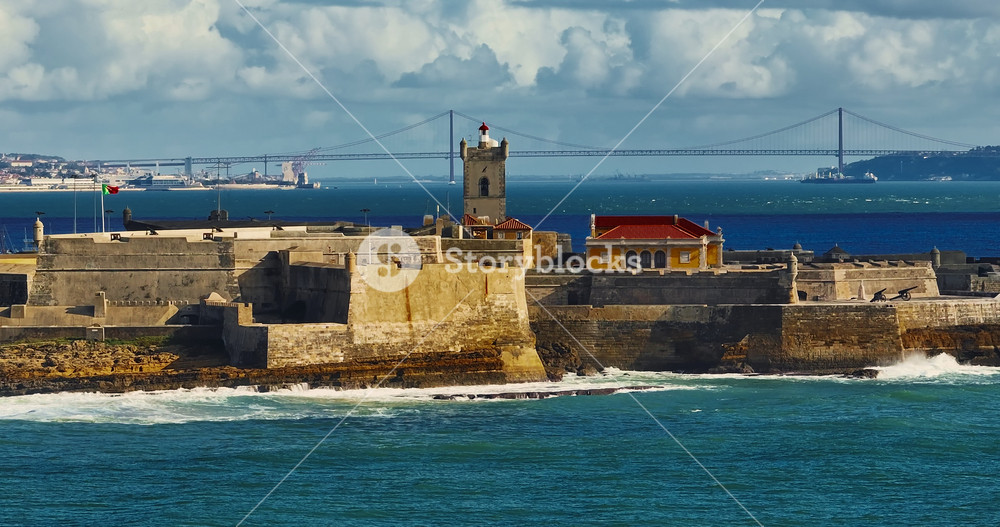 Drone view of a fortress in Portugal with the famous bridge in the background. Saint Julian Fortress with lighthouse tower from beach of