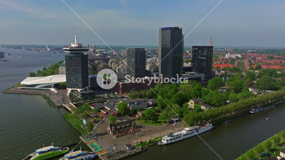 Aerial view of the European tourist city of Amsterdam. A drone flies over the city center at sunset. Establishing shot of the main and famous city in the Netherlands. Narrow canals divide the city