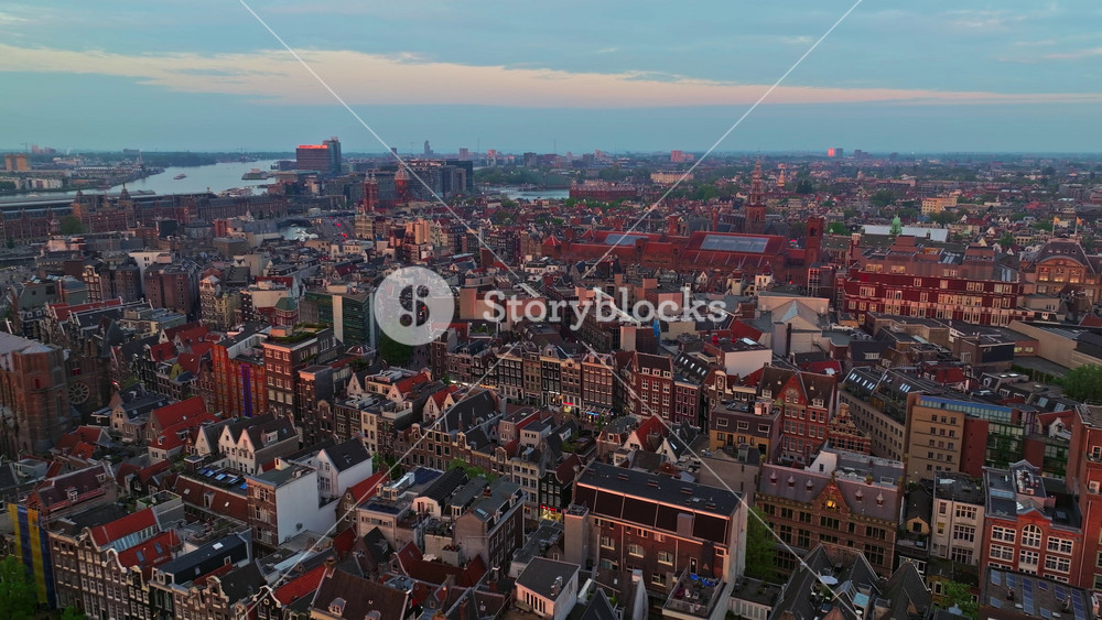 Drone shot Amsterdam summer cityscape narrow old houses, canals. Aerial view of famous places Amsterdam, Netherlands. Top view of rows of stunning sharp roofs and facades of high modern buildings