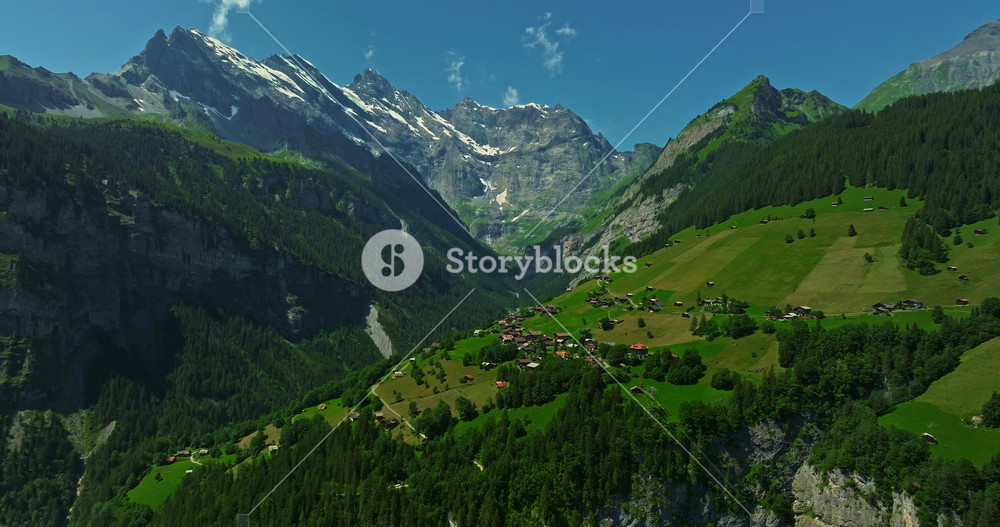 Aerial view of the small village of Gimmelwald. Swiss mountain village with traditional houses against snowy mountains. Green alpine valley