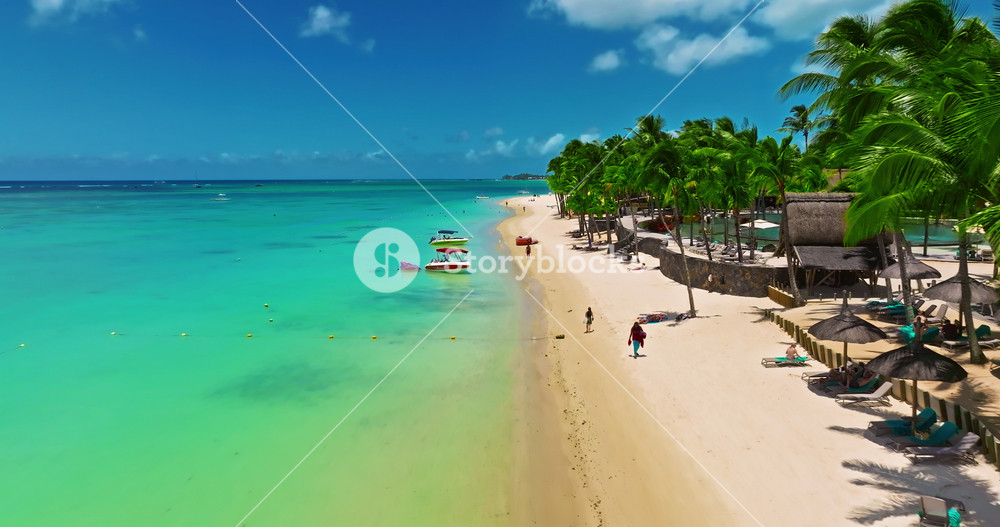 Aerial view of crystal water on the seashore, Mauritius with palm trees and living reef around the island. Establishing shot of sea lagoon