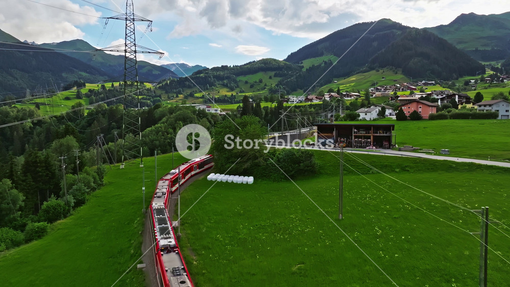 Aerial drone shot red train passing through famous mountain in Filisur, Switzerland. Drone footage of train traveling between mountains in Swiss countryside, Swiss mountain. Aerial drone Switzerland