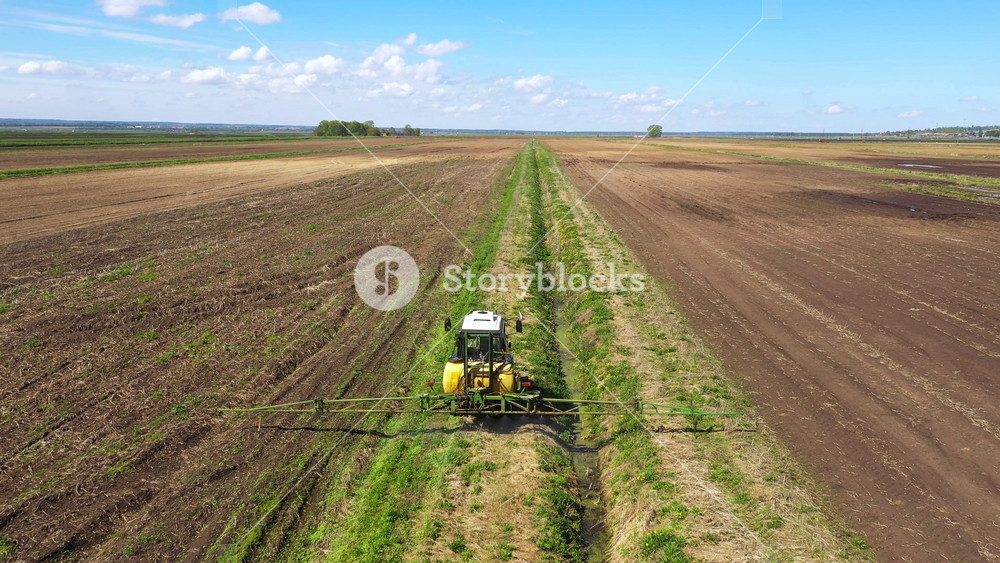 Spraying with pesticides and herbicides crops aerial view. Tractor with pesticide fungicide insecticide sprayer on farm land.