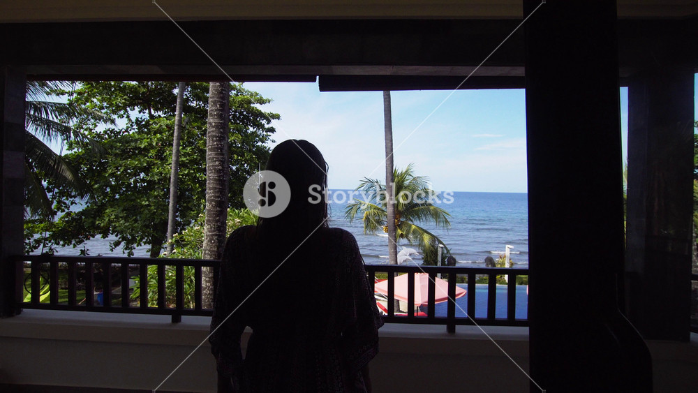 Girl goes to the balcony, the terrace of the luxury hotel and looks at the sea. beautiful young girl standing on the balcony and looking at