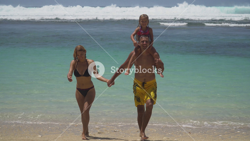 Happy beautiful family with child walking together on tropical beach during summer vacation. Bali. Family of three having fun on tropical