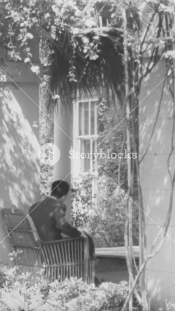 1940s - People walk through luxurious yards of wealthy homes in Charleston, South Carolina, and cars drive by on tree-lined streets.