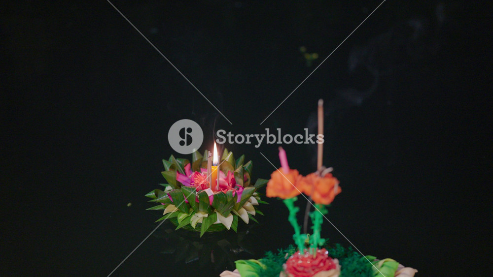 A beautifully decorated krathong with a burning candle and incense floats on still water, symbolizing hope and gratitude during the enchanting Loy Krathong festival in Thailand