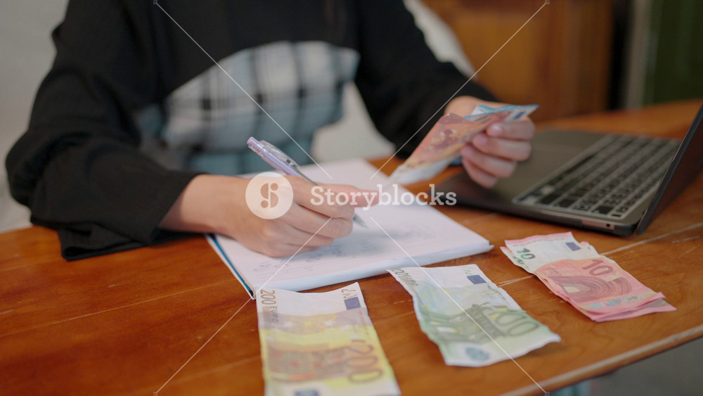 Worried Asian woman counting money with a serious expression. She calculates the household budget to manage rising expenses and financial struggle caused by the global economic crisis.