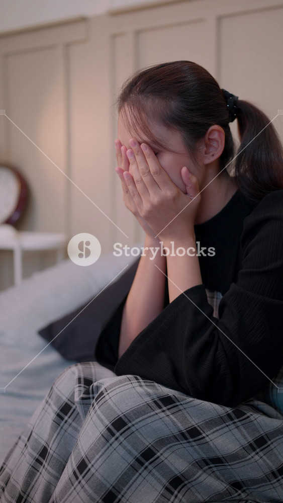 Financial stress concept where an Asian single mom calculates household expenses. Worried about bankruptcy and unemployment, she faces the pressure of rising daily living costs at home.