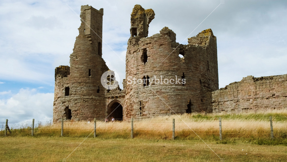 DUNSTANBURGH, United Kingdom, circa 2022 - Establishing shot of Dunstanburgh Castle, a 14th-century fortification on the coast of Northumberland in northern England, UK