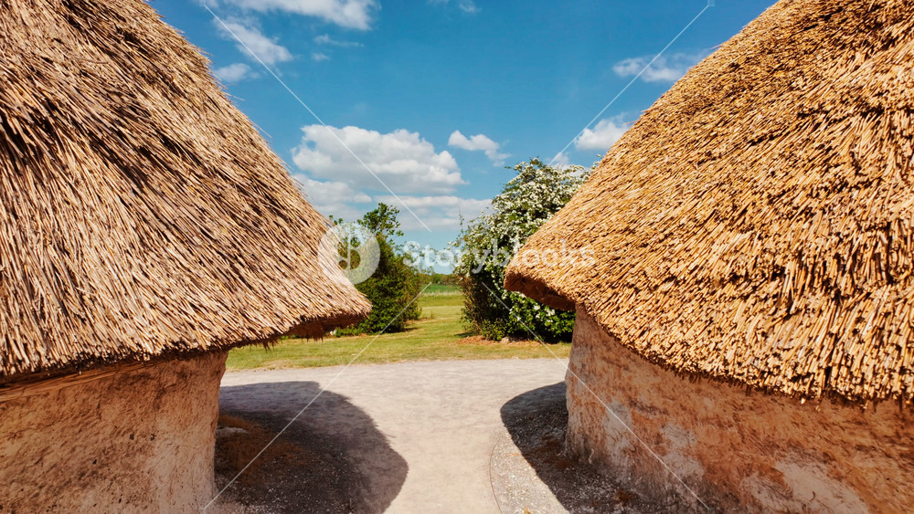 SALISBURY, United Kingdom, 12 MAY 2025 - Primitive timber framed huts and earth mounds adjacent to prehistoric stones, Neolithic Houses in Stonehenge, Salisbury, Wiltshire, England, UK
