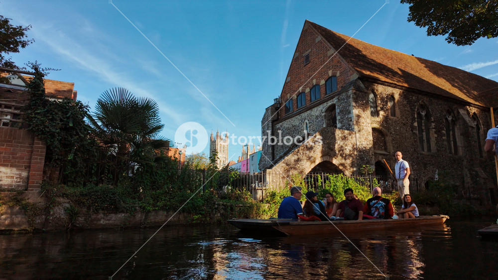 CANTERBURY, United Kingdom, 12 August 2025 - Punt boat with cheerful tourists on the Great Stour, Canterbury, Kent, England, UK, gliding past historic architecture, timber fronts and riverside lawns