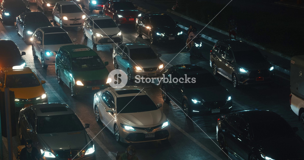 Rush hour traffic on highway of big city at night time. Commuters drive through central Bangkok. Cars and mopeds drives through central