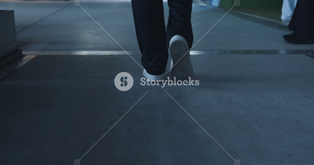 Rear back view feet of man commuting to work. Confident guy in in sneakers shoes feet of man and suit being on his way to office building