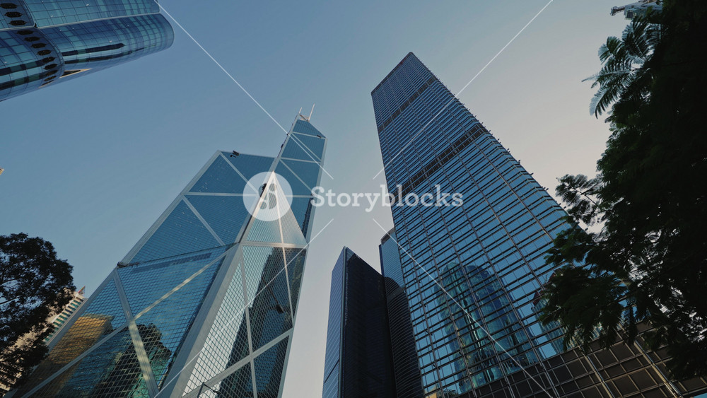 Modern skyscrapers with glass overall in Hong Kong downtown at sunset low angle shot. Highrise commercial buildings located in Asian
