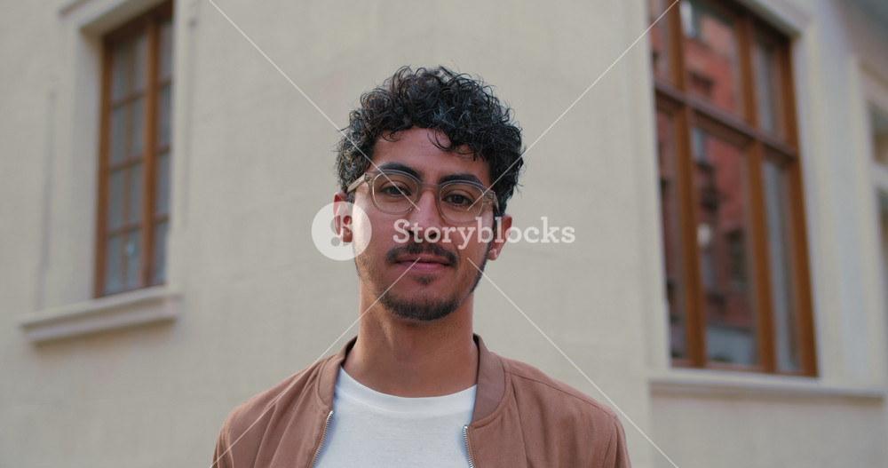 Portrait of handsome young guy in glasses looking to camera. Close up view of millennial bearded man smiling. Outdoors. Concept of people