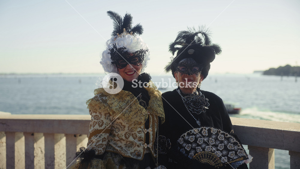 VENICE, ITALY - MARCH 05 2024: Portrait of happy mother and adult daughter in medieval dresses stand on Ponte Della Paglia bridge. family in