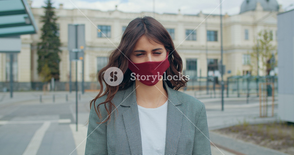 Portrait of pretty woman in reusable handmade mask looking to camera. Crop view of millennial girl with long brown hair wearing cotton face