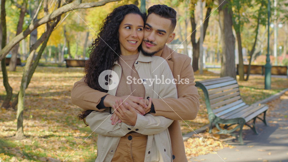 Hispanic couple hugging in autumn park man guy hug beloved girl woman from behind back in autumnal city outdoors embracing enjoy